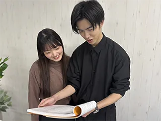 参考書を開いて解き方を説明する講師と生徒